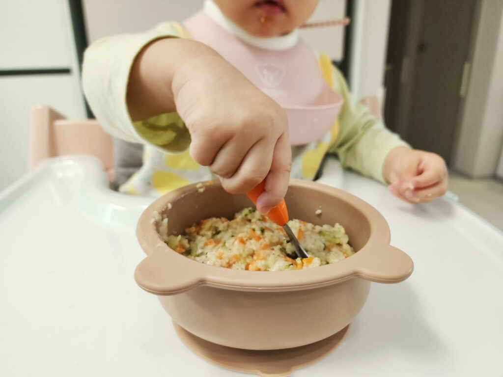 아이가 숟가락을 들고 당근브로콜리죽을떠먹는 식사 과정